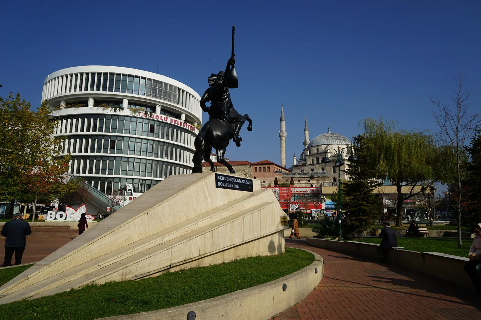 Bolu şehir merkezinde şahlanan atın üzerindeki Köroğlu heykeli, arkada yuvarlak cepheli bina